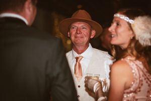 A guest in a cowboy hat and white suit jacket mingles at an evening party.