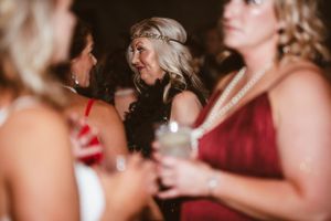 Guests in vintage-inspired formal wear engage in animated conversation at an evening party.