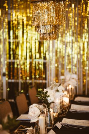 Gold shimmer curtains and elegant table settings with candlelight creating a glamorous atmosphere.