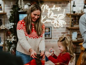 Adult and child in festive sweaters share a holiday moment together.