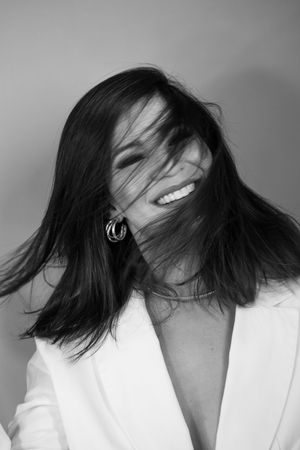 Dynamic black and white photo showing hair in motion with natural lighting and white jacket.