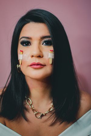 Black-haired woman with bold makeup and chain necklace poses for beauty portraits.