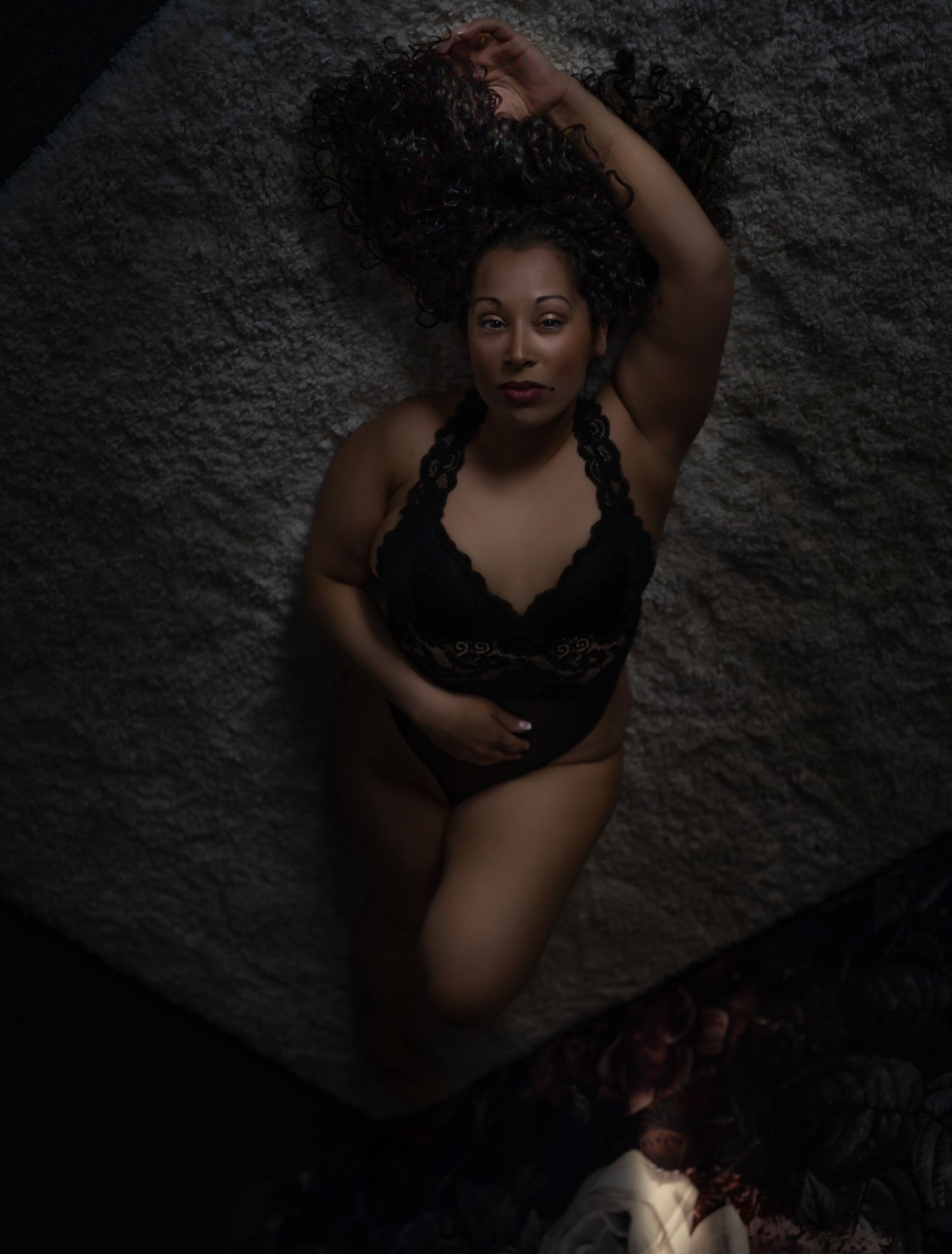 Artistic boudoir photography with dramatic lighting against a dark textured background.