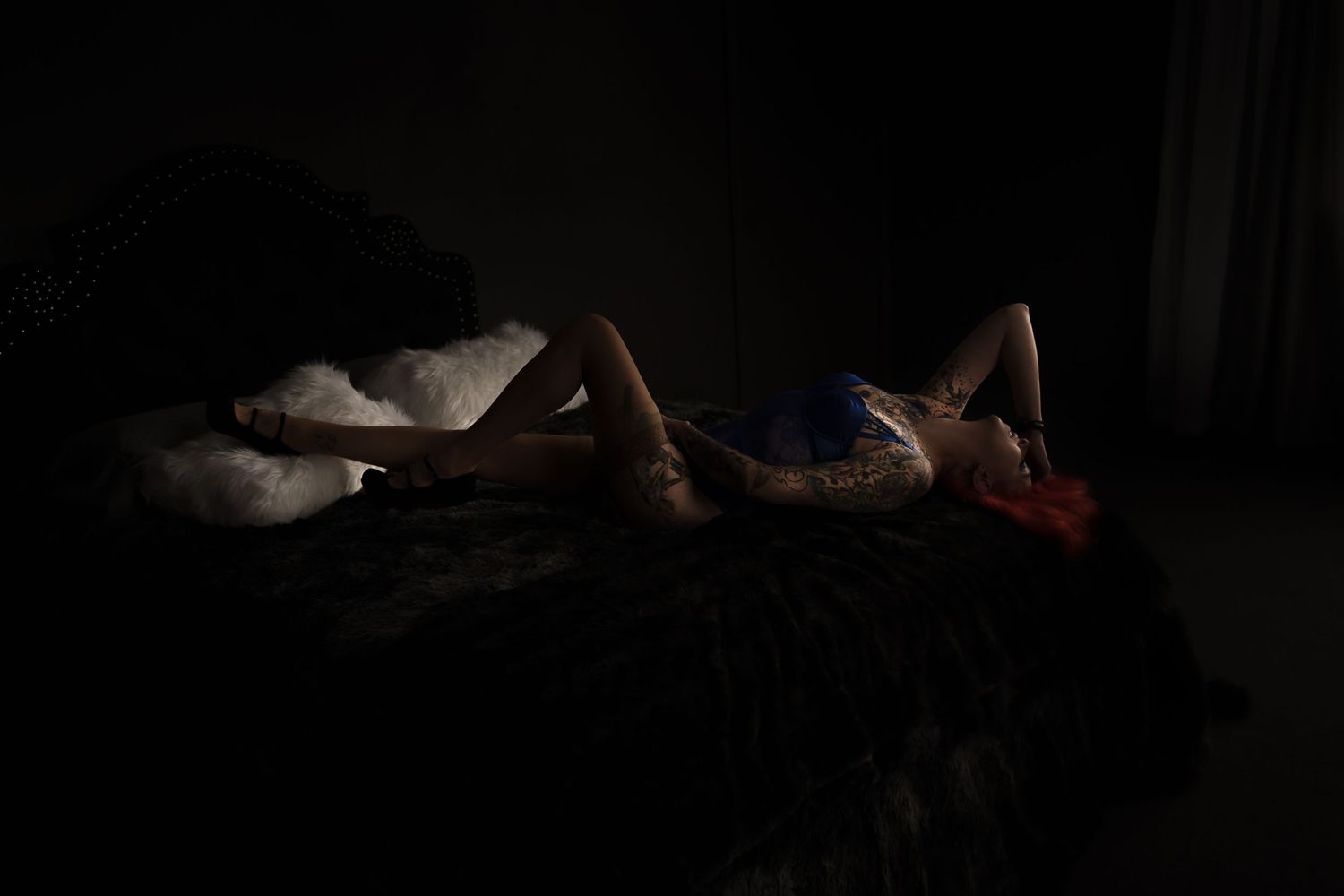 Artistic low-key boudoir photography with dramatic shadows.