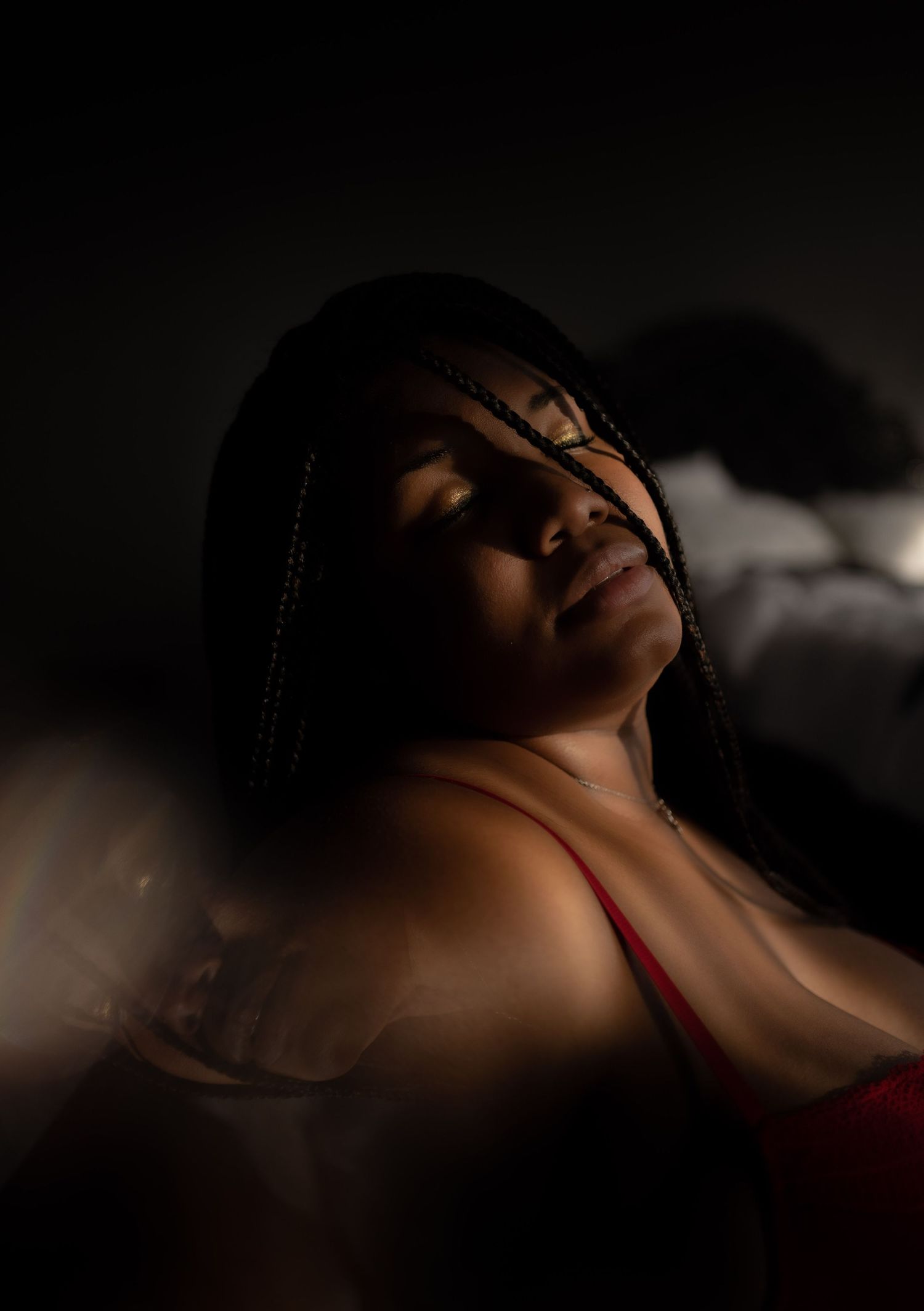 Intimate portrait with dramatic side lighting creating soft shadows.
