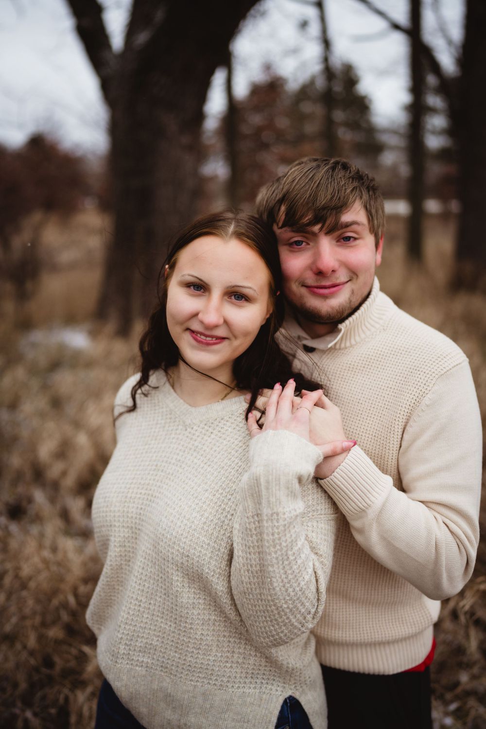 Couple in matching cream sweaters sharing an intimate moment outdoors.