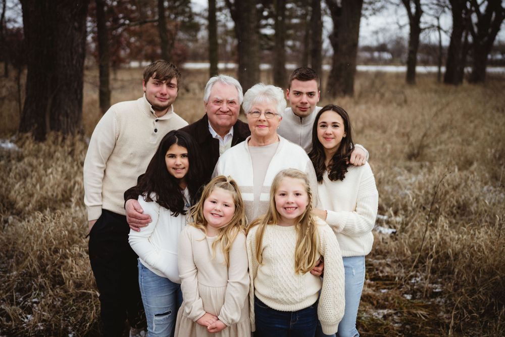 Multi-generational group poses together in winter field wearing coordinated cream-colored sweaters.