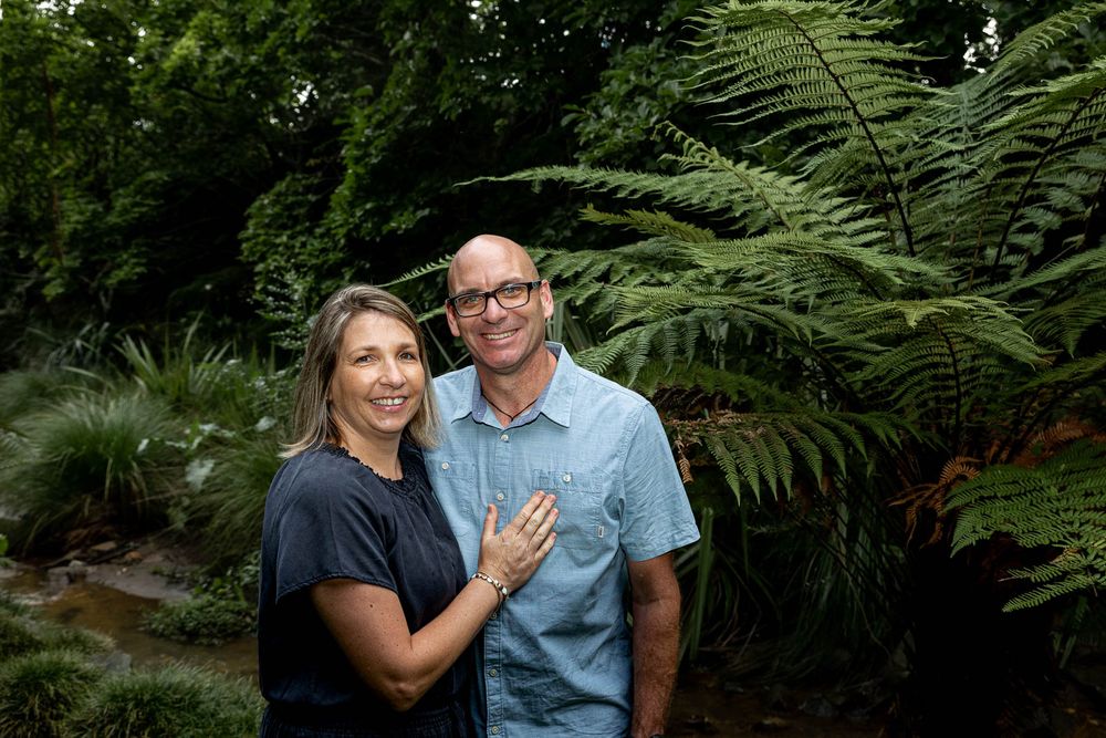 Loved up couple smiling in front of many green ferns and creek in park