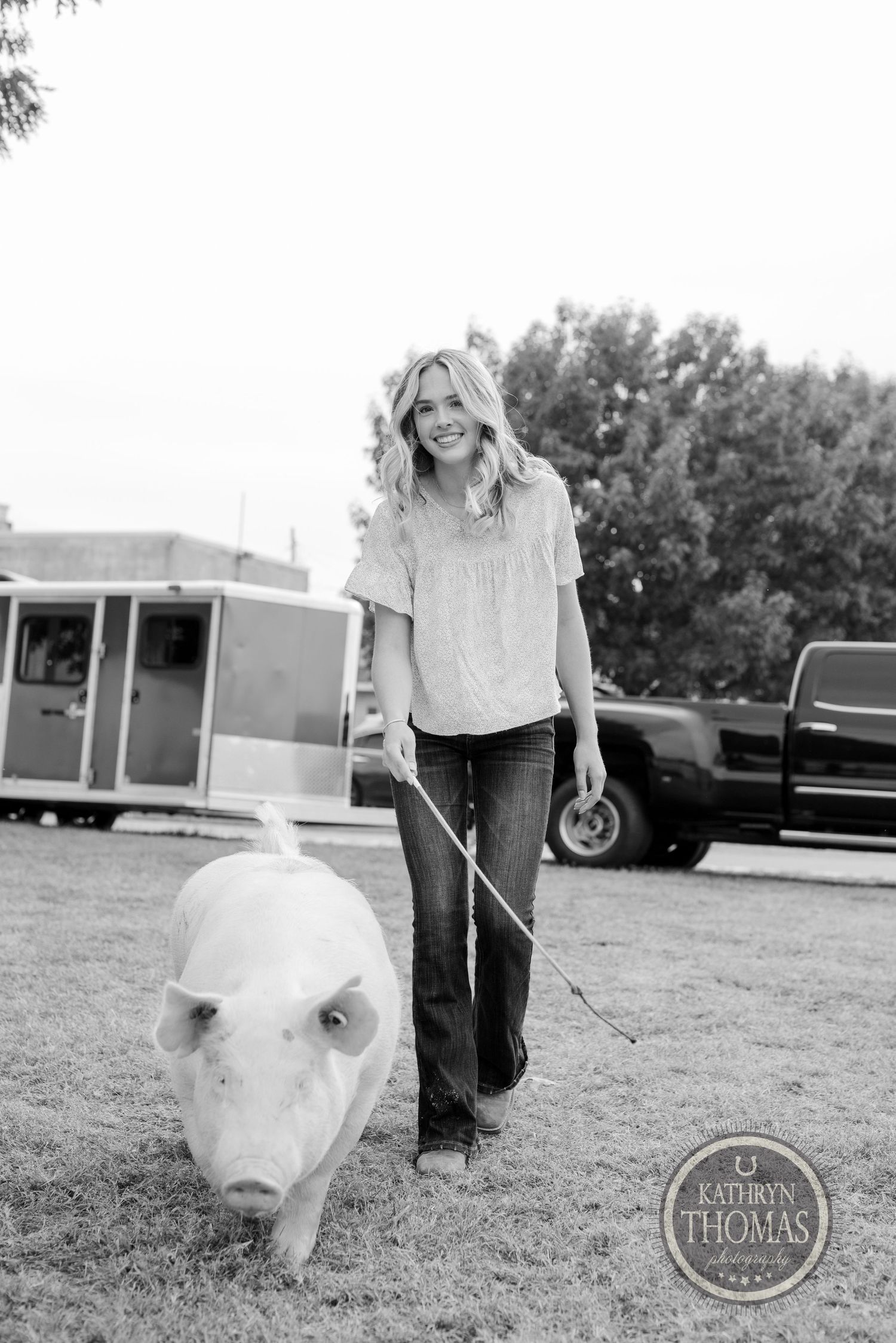 A black and white photo shows a pig being walked on a lead rope outdoors.