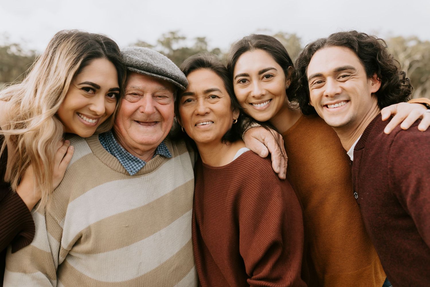 Casual family portrait with everyone wearing coordinating earth-toned sweaters.