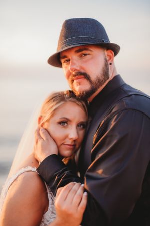 Romantic sunset portrait of couple with man wearing fedora hat.