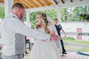 A couple shares their first dance at an outdoor wedding reception.