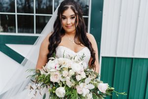 An elegant bridal portrait featuring a stunning white bouquet and flowing tulle wedding gown.