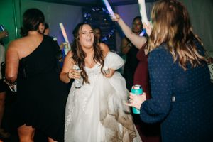 Celebration at wedding reception with glowing neon party sticks on dark dance floor.