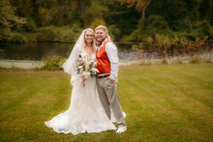 Wedding portrait by lake with couple in lace gown and casual attire during fall season.