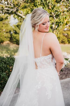 Back view of lace wedding dress with delicate spaghetti straps and flowing veil.
