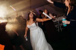 Energetic dance floor scene at wedding reception with colorful light sticks.