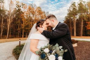 A joyful wedding embrace captured on a winding path with autumn trees in the background.