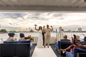 Wedding celebration aboard a boat with city skyline views at sunset.