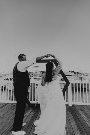 A couple sharing a dance together on a waterfront deck in black and white.
