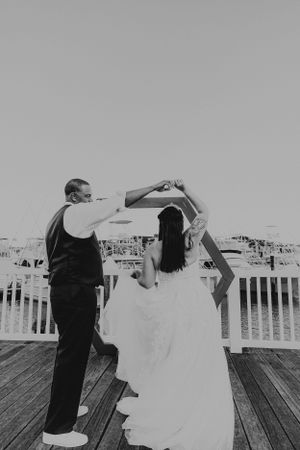 Bride and groom dancing on marina boardwalk in monochrome.