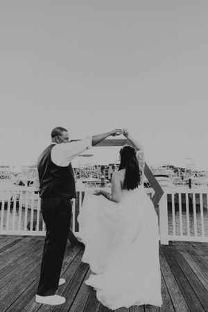Wedding dance captured in black and white on waterfront boardwalk.