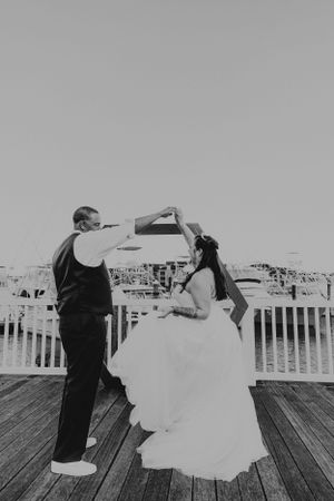 Dancing bride and groom on boardwalk in black and white.