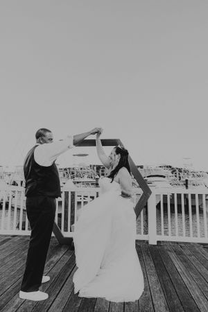 Couple dancing on boardwalk in black and white wedding photo.