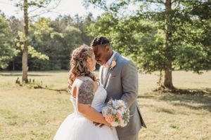 Romantic outdoor wedding portrait in sunlit garden setting.
