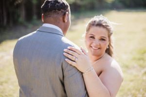 A couple shares a tender moment during their outdoor wedding photoshoot in natural sunlight.