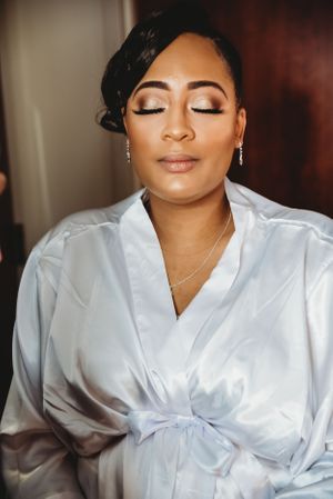 Close-up of bridal makeup with shimmering eyeshadow and silk robe during wedding preparations.
