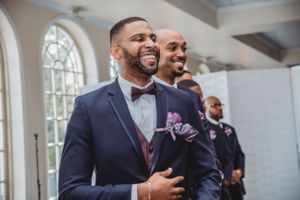 Wedding ceremony with groomsmen in navy suits and purple accents.