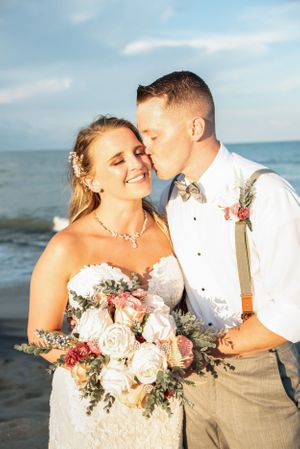 A beachside wedding portrait with soft lighting and a beautiful bouquet of blush roses.