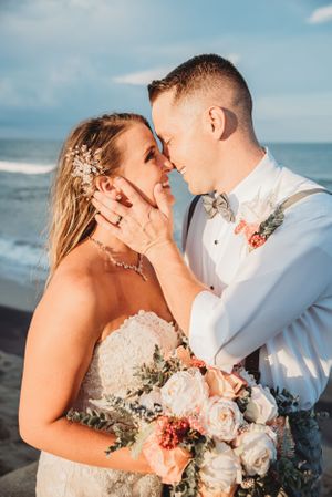 Romantic beach wedding portrait with bouquet and sunset lighting.