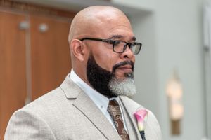 Formal portrait of wedding guest in light grey suit with pink boutonniere.