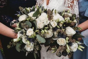 A detailed close-up of a white and green wedding bouquet with roses and mixed florals.