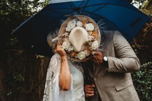 A romantic moment shared under a blue umbrella during a wedding photoshoot.