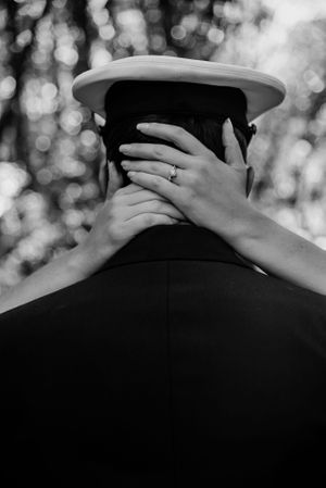 A black and white romantic photo showing hands embracing from behind.