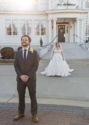 Wedding first look scene with couple at elegant white mansion entrance.