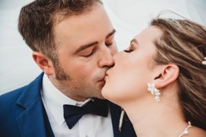 Close up romantic seaside wedding kiss with bride and groom.