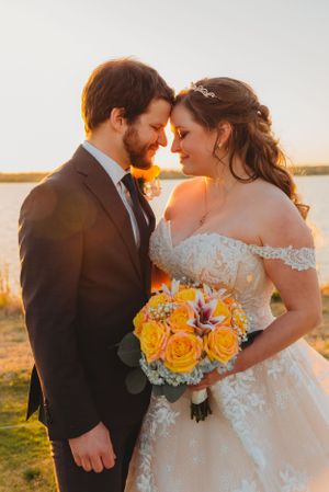 Tender wedding moment captured during golden hour with yellow rose bouquet and lace dress details.