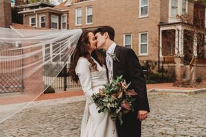 Urban winter wedding scene with couple sharing romantic moment on cobblestone street.