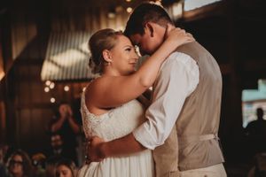A couple shares their first dance at a rustic wedding reception venue.