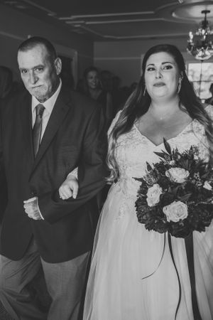 A formal wedding processional moment captured in black and white photography.