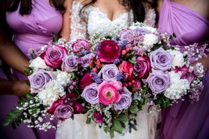 Stunning wedding bouquet featuring purple and pink roses with baby's breath.
