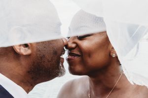 An intimate moment between newlyweds captured under flowing white veils.