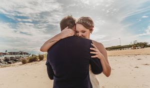 Intimate embrace between newlyweds on a beach during sunset.