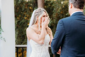Emotional wedding moment captured during outdoor ceremony by white pillars.