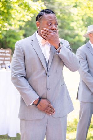 Emotional moment captured as a person in grey suit covers their mouth in surprise.