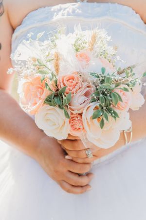 Beautiful bridal bouquet with peach and white roses against a soft background.